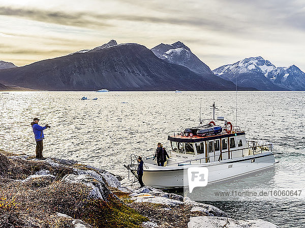Touristen mit ihrem Ausflugsboot entlang der zerklüfteten Küstenlinie,  die ihr Ausflugsboot und die Landschaft fotografieren; Nuuk,  Sermersooq,  Grönland