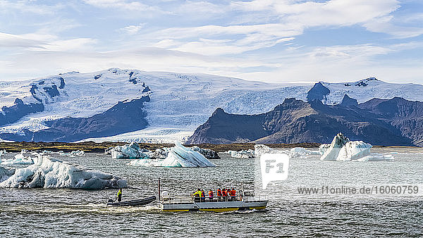 Ausflugsboot im Gletschersee  Jokulsarlon  Vatnajokull-Nationalpark. Die Gletscherlagune fließt durch einen kurzen Wasserweg in den Atlantischen Ozean und hinterlässt Eisbrocken an einem schwarzen Sandstrand; Hornafjordur  östliche Region  Island
