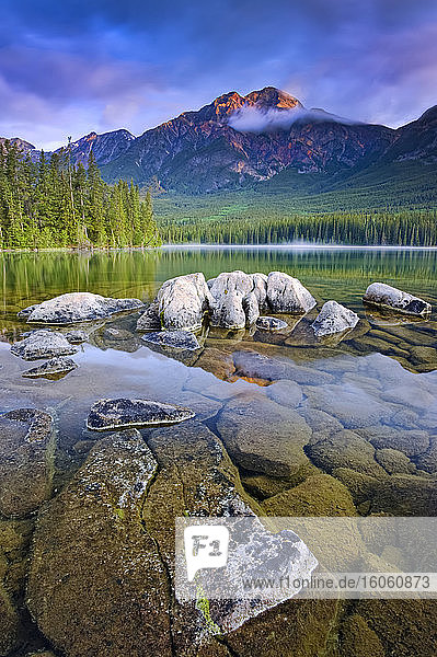 Morgenrot auf den zerklüfteten Rocky Mountains mit klarem  ruhigem Seewasser im Vordergrund  Jasper-Nationalpark; Alberta  Kanada