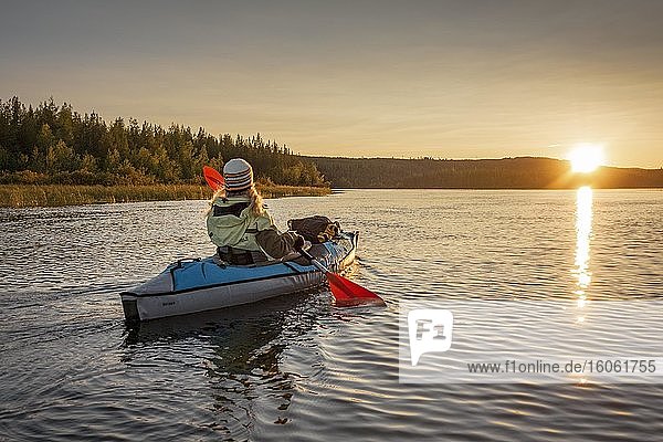 Kajakerin  Ende vierzig  blond  paddelt mit aufblasbarem Kajak bei Sonnenuntergang auf einem See in Abendstimmung  Muddus Nationalpark  Jokkmokk  Norrbottens län  Schweden  Europa