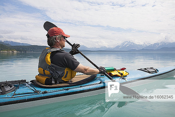 Man sea kayaking calm waters of an inlet in a national park.