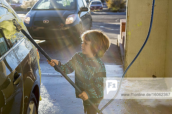 4 Jahre alter Junge  der in einer Autowaschanlage ein Auto wäscht