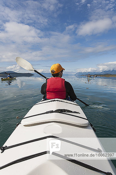 Eine kleine Gruppe von Menschen paddelt in den unberührten Gewässern einer Bucht an der Küste Alaskas.