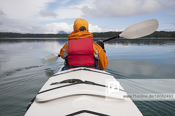 Woman sea kayaking calm waters of an inlet in a national park.