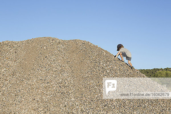 4 Jahre alter Junge klettert auf einen Kieshügel