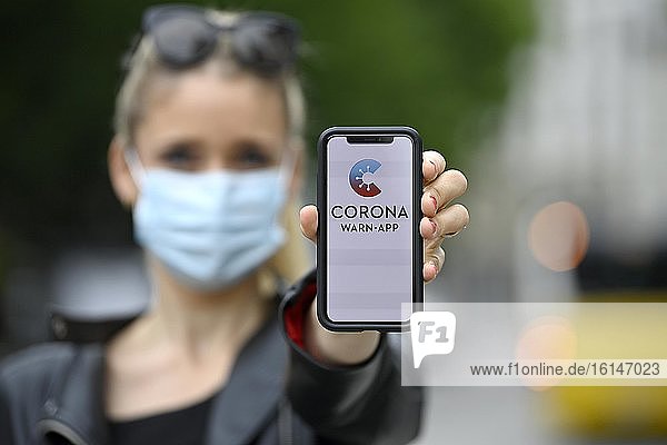 Frau mit Mundschutzmaske  zeigt Smartphone mit Corona Warn-APP  Corona-Krise  Baden-Württemberg  Deutschland  Europa