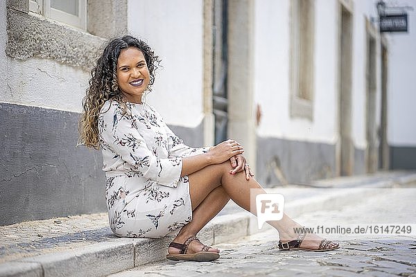 Schöne Frau sitzt auf dem Bürgersteig einer portugiesischen Straße  Portugal  Europa