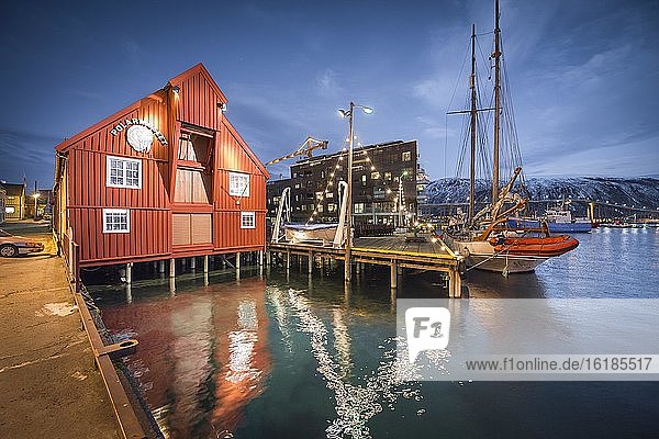 Polarmuseum am Hafen mit Spiegelung im Meer in Abenddämmerung, Polarnacht, Tromsö, Troms, Norwegen, Europa