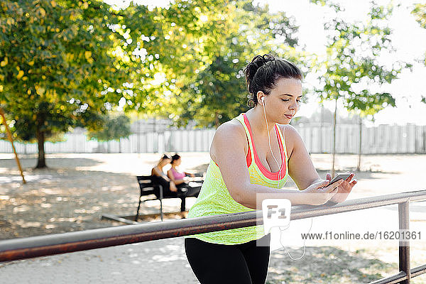 Frau benutzt Handy im Park  Freunde machen im Hintergrund Pause