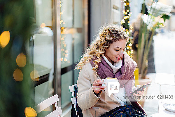 Woman using smartphone and having hot drink at cafe  Firenze  Toscana  Italy
