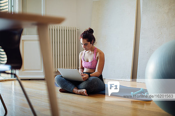 Woman using laptop in exercise clothes
