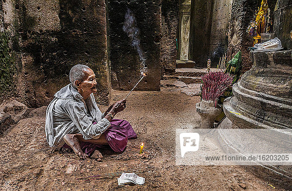 Devotee nun  lighting incense and offering prayers at Preah Khan Temple  Angkor  Cambodia