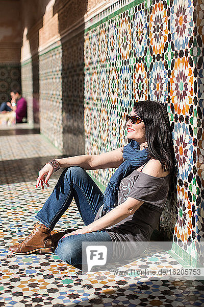 Seitenansicht einer Frau  die an einer gefliesten Wand sitzt  Ben Youssef Madras  Marrakesch  Marokko