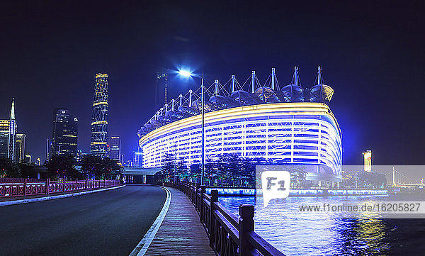 Beleuchtetes Olympiastadion am Flussufer bei Nacht,  Guangzhou,  China