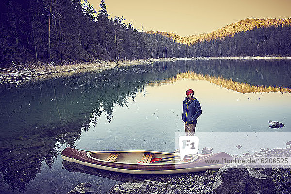 Man beside canoe, Eibsee Lake at base of Zugspitze, Garmisch-Partenkirchen, Bavaria, Germany
