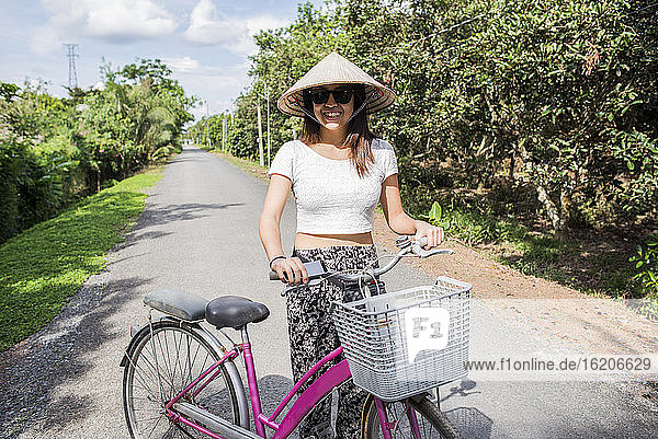 Frau mit traditionellem Reishut neben einem Fahrrad  Insel Tan Phong  Vietnam