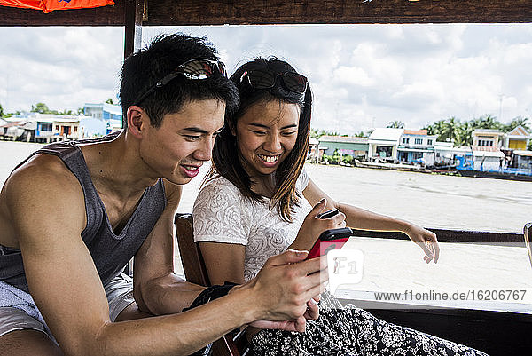 Ein Paar betrachtet ein Handyfoto auf einem Kreuzfahrtschiff  Mekong-Delta  Vietnam