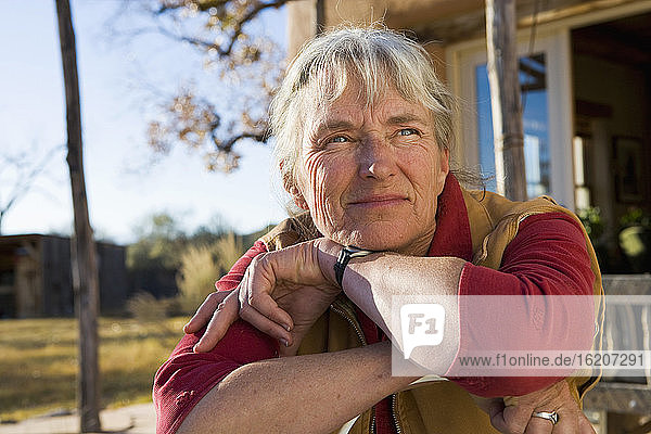 Mature woman at home on her property in a rural setting resting her chin on her hands