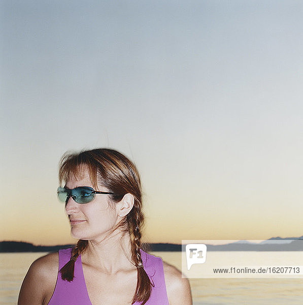 Portrait of woman wearing sunglasses  ocean in distance