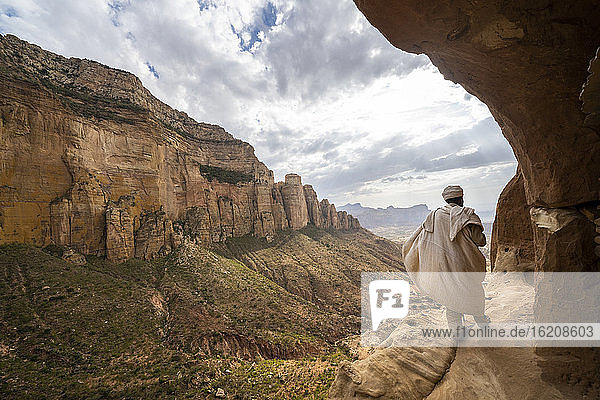 Rückansicht eines Priesters  der auf dem Zugangsweg zur in den Fels gehauenen Abuna-Yemata-Guh-Kirche geht  Gheralta-Gebirge  Region Tigray  Äthiopien  Afrika