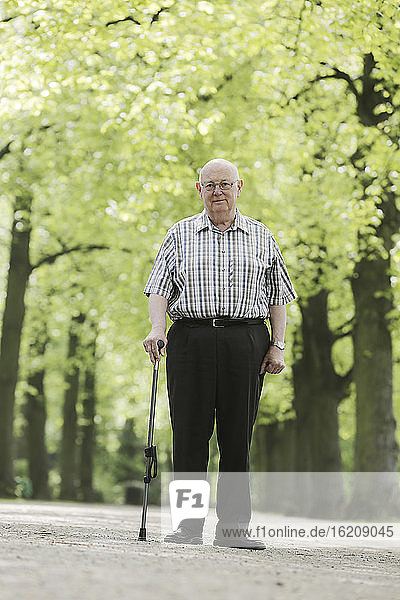 Deutschland  Nordrhein-Westfalen  Köln  Porträt eines älteren Mannes mit Spazierstock im Park  lächelnd