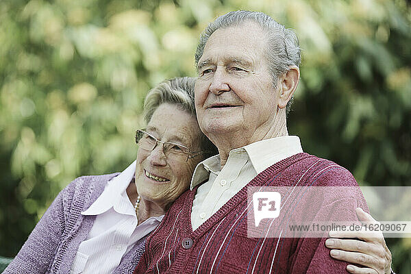 Deutschland  Köln  Älteres Paar sitzt im Park  lächelnd