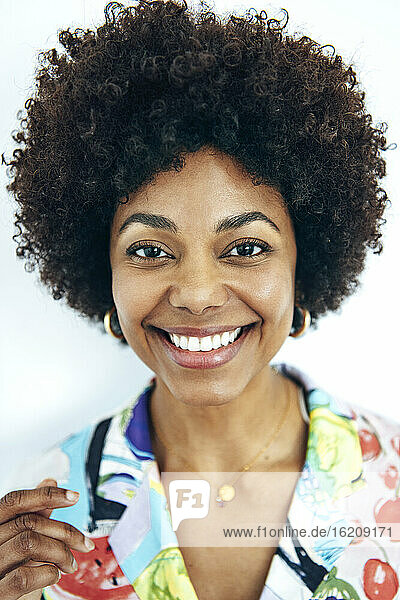 Glückliche Frau mit Afrofrisur vor weißem Hintergrund
