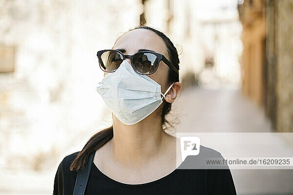 Porträt einer Frau mit Sonnenbrille und Schutzmaske in der Stadt