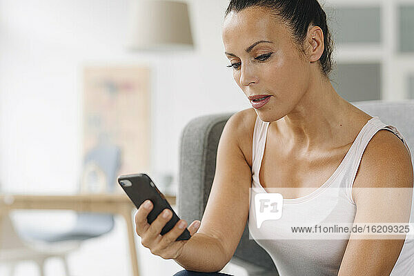Close-up of businesswoman using smart phone while sitting at home