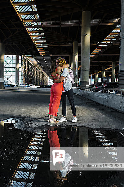 Paar umarmt einander mit Reflexion auf Pfütze in der Stadt