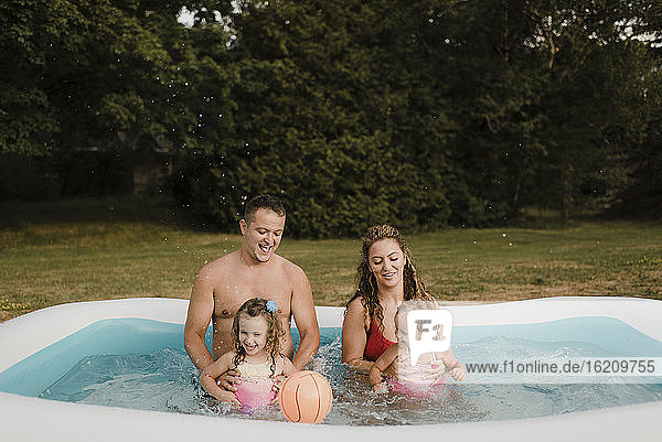 Glückliche Familie in einem aufblasbaren Schwimmbad im Garten