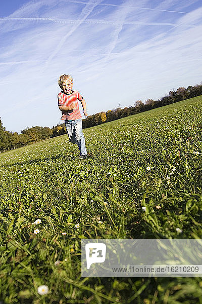 Little boy (4-5) running across meadow