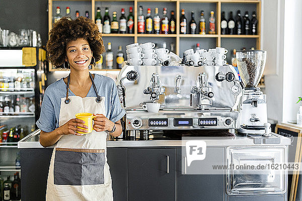 Glückliche weibliche Barista hält Kaffeebecher im Café
