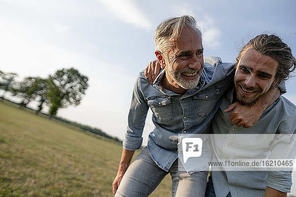 Glücklicher Vater und erwachsener Sohn spielen auf einer Wiese auf dem Lande miteinander