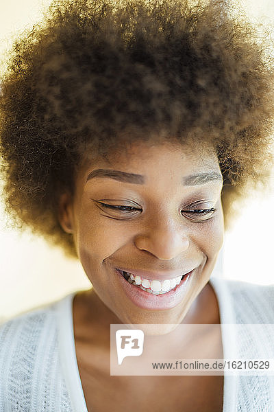 Nahaufnahme einer lächelnden Frau mit Afro-Haar  die auf ihr Zuhause blickt