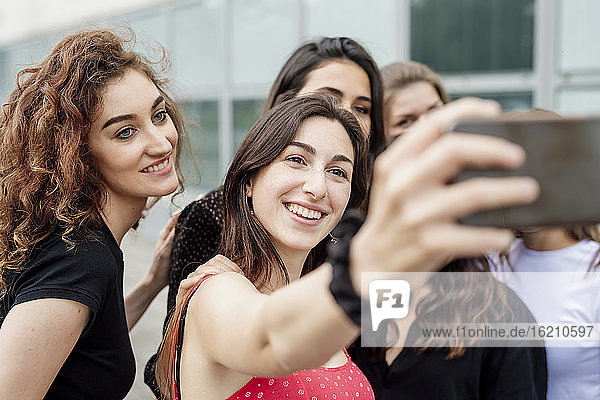Young woman taking selfie with female friends in city