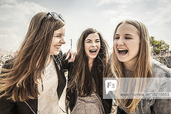 Three laughing teenage girlfriends outdoors
