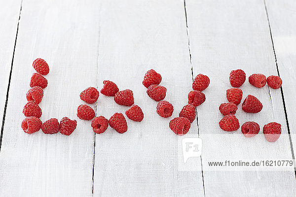 Mit Himbeeren geformter Text auf Holztisch  Nahaufnahme