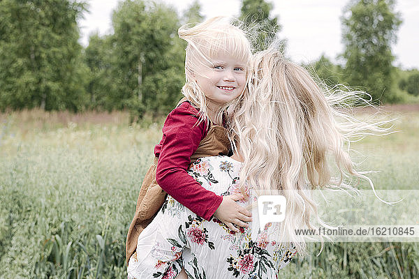 Junge Frau mit blondem Haar und süßer Tochter im Haferfeld stehend