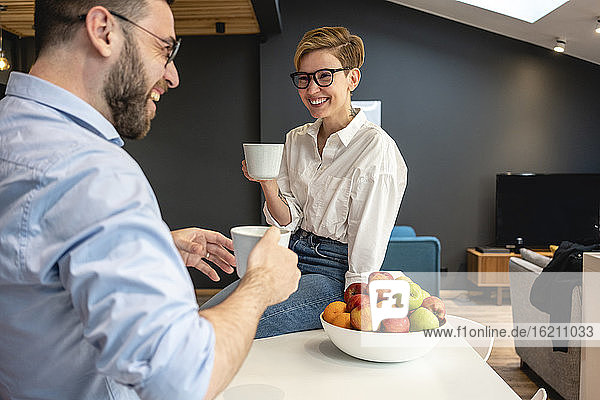 Glückliche weibliche und männliche Fachkräfte genießen die Kaffeepause in der Büro-Cafeteria