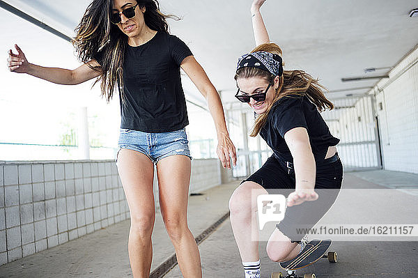 Junge Frau  die in einer Unterführung Skateboard fährt