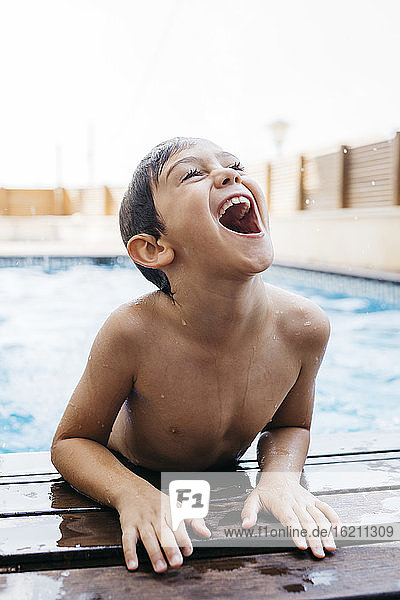 Fröhlicher Junge  der am Pool aufsteht