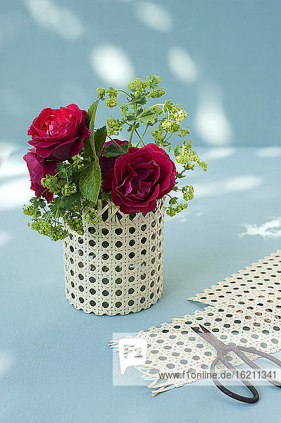 Rote Rosen in einer Vase aus einem Marmeladenglas und Wiener Zopf und Schere