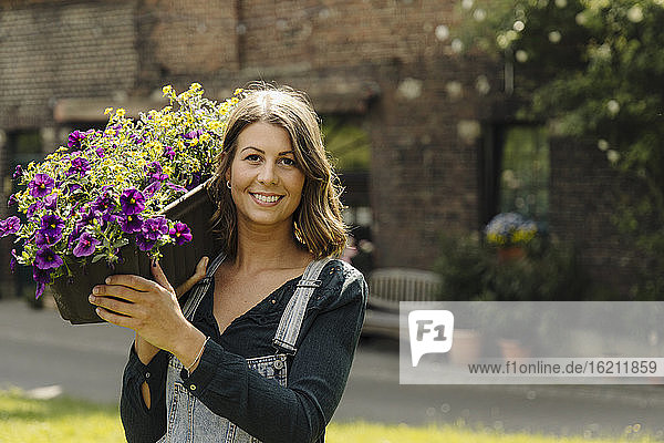 Porträt einer lächelnden jungen Frau mit Blumenkasten