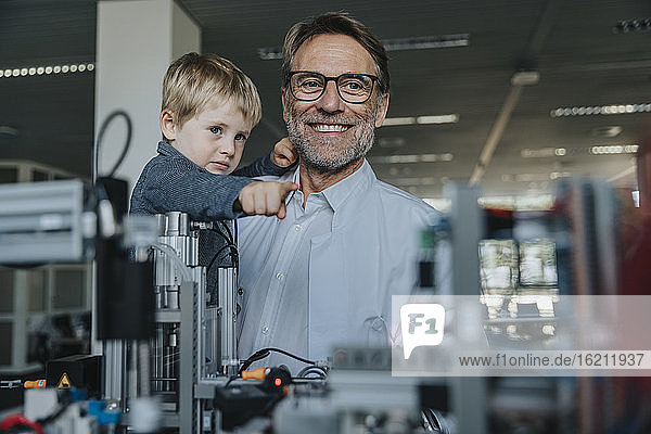 Ein Vater zeigt seinem Sohn in einem Labor in einer Fabrik Maschinen