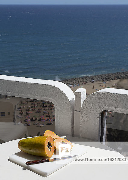 Spanien  Gran Canaria  Papaya mit Messer auf Tisch in Strandnähe
