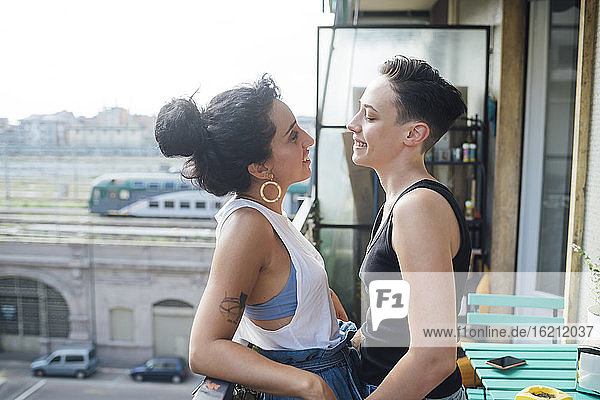 Lächelnde lesbische Frauen im Gespräch auf dem Balkon