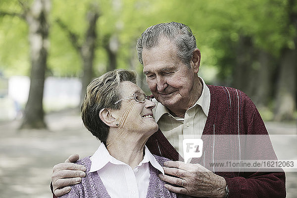 Deutschland  Köln  Älteres Paar sieht sich im Park lächelnd an