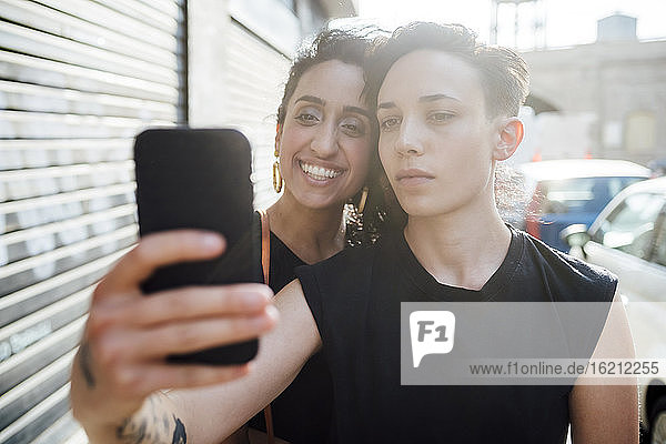 Smiling woman and partner taking selfie in city