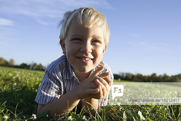 Kleiner Junge (2-3 Jahre) auf der Wiese liegend  lächelnd  Porträt